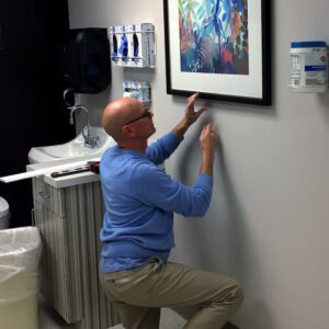 our corporate art consultants help you determine where and what to hang just as Tom is doing here